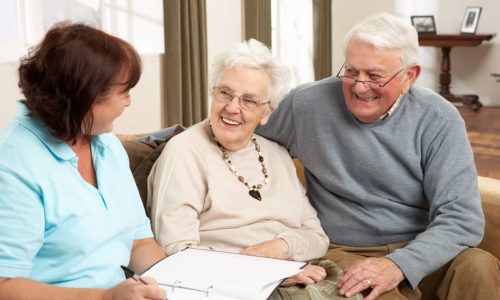 Senior Couple In Discussion With Health Visitor At Home